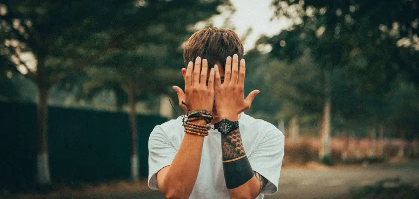 Ragazzo tatuato che si copre il viso con le mani – Cura del tatuaggio