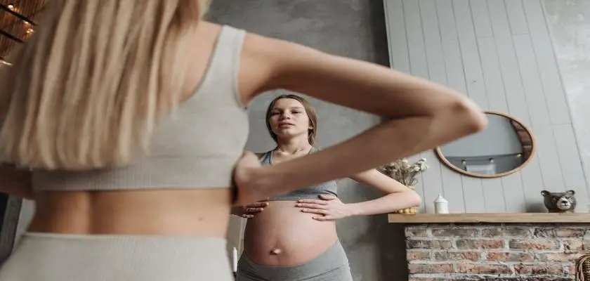 Donna incinta che si guarda il pancione allo specchio