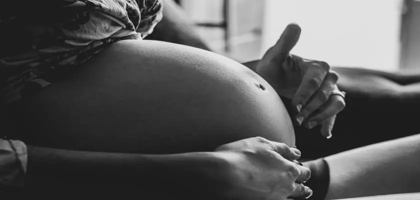 Donna incinta seduta sul divano – Tatuaggi in Gravidanza