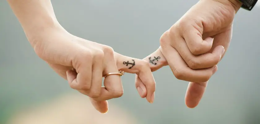 Due mani con piccoli tatuaggi sugli indici delle dita