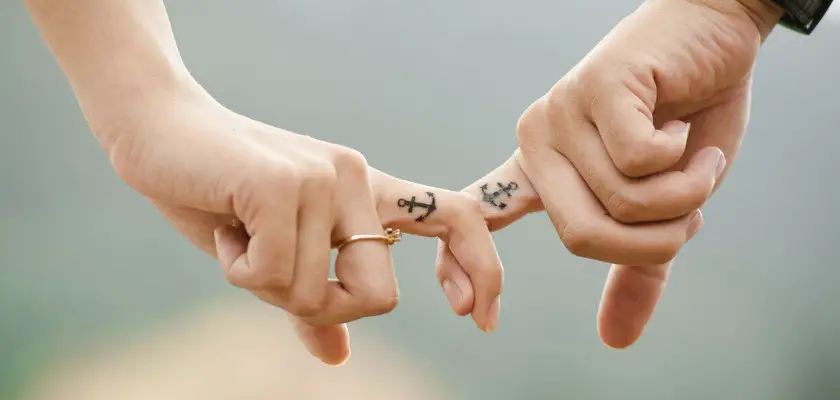 Due mani con piccolo Tatuaggio ad Ancora sull’indice