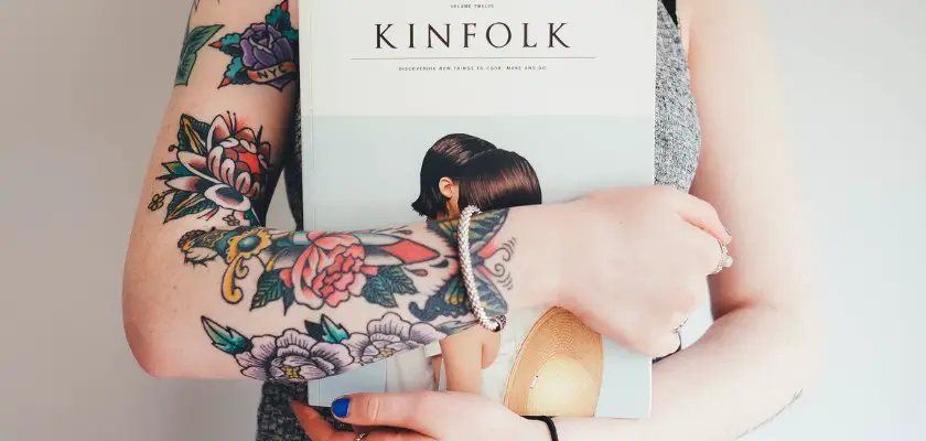 Ragazza tatuata che stringe un libro sul suo petto