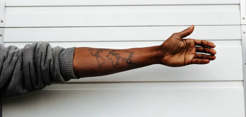 Ragazzo di colore che mostra il suo braccio sinistro tatuato