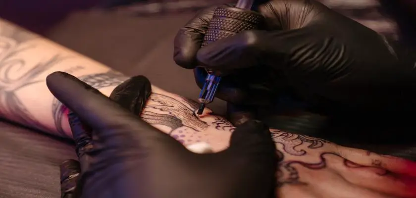 Tatuatore che effettua un tatuaggio sul braccio