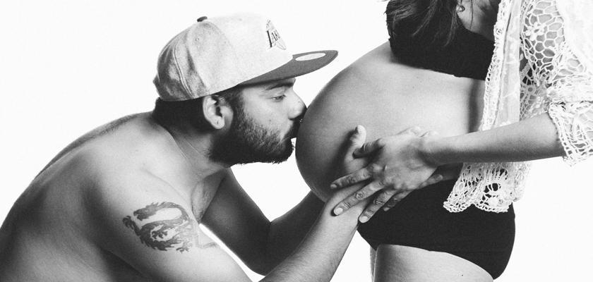 Uomo che bacia il pancione della sua donna incinta – Tatuaggi in Gravidanza