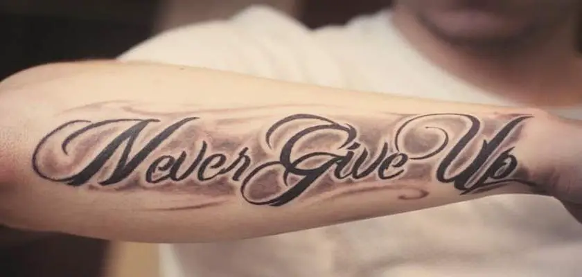 Uomo che mostra il suo tatuaggio (Never Give Up) situato sul suo braccio destro – Tatuaggi Uomo