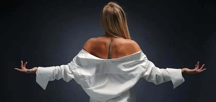 Bionda in piedi con entrambe le braccia distese vista di spalle – Tatuaggio schiena donna