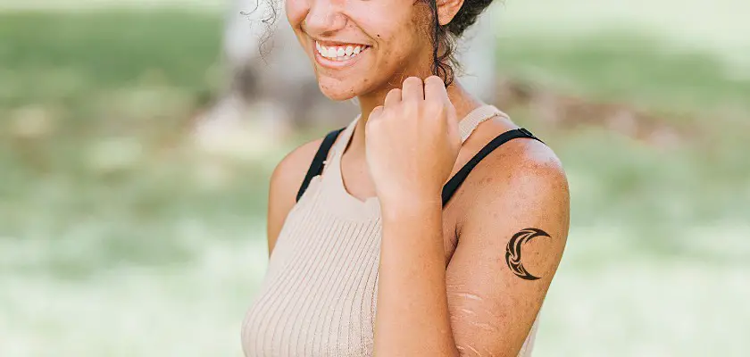 Ragazza sorridente con un tatuaggio luna celtica sul braccio sinistro