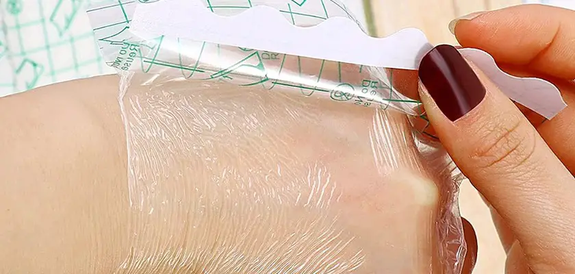 Ragazza che si toglie la pellicola trasparente protettiva per tatuaggi dalla mano sinistra – Ogni quanto lavare il tatuaggio