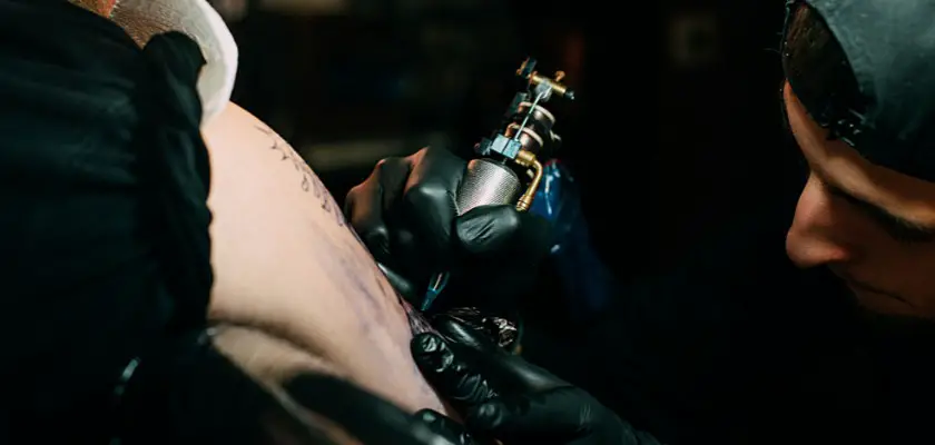 Vista parziale di un tatuatore professionista mentre effettua un tatuaggio sul braccio del suo cliente – Tatuaggio appena fatto