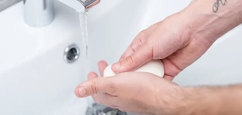 Vista parziale di un uomo mentre si lava le mani con il sapone sul lavandino