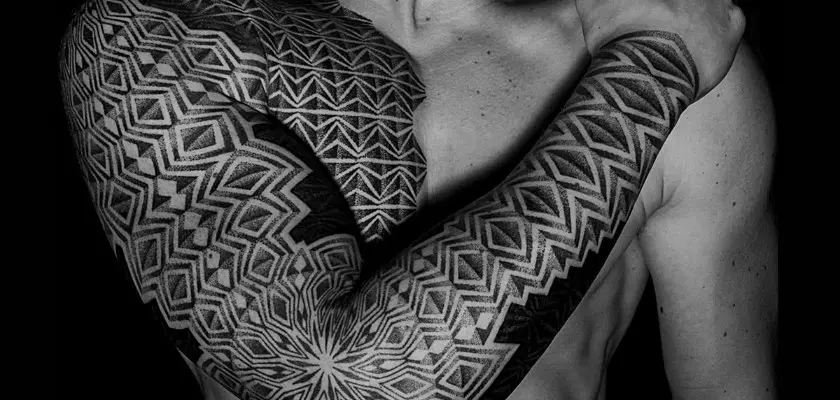 Vista superiore parziale di un uomo con le braccia tatuate con la tecnica Dotwork Tattoo