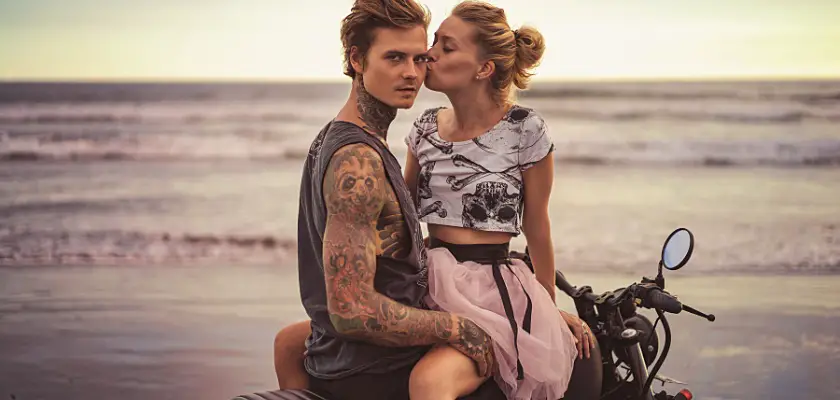 Coppia di fidanzati seduti sul sedile della moto in spiaggia mentre si baciano