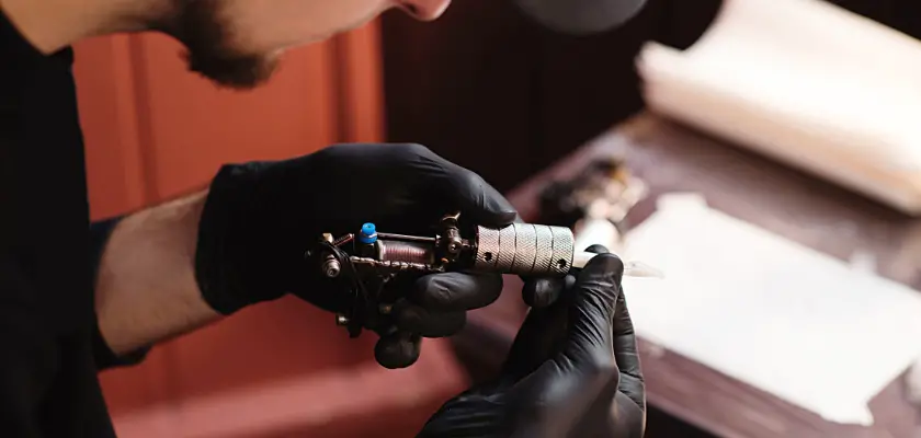 Focus selettivo di un tatuatore mentre tiene nelle mani una macchina per tatuaggi