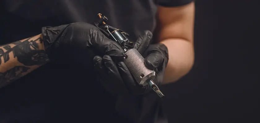 Vista parziale di un tatuatore con una macchinetta per tatuaggi