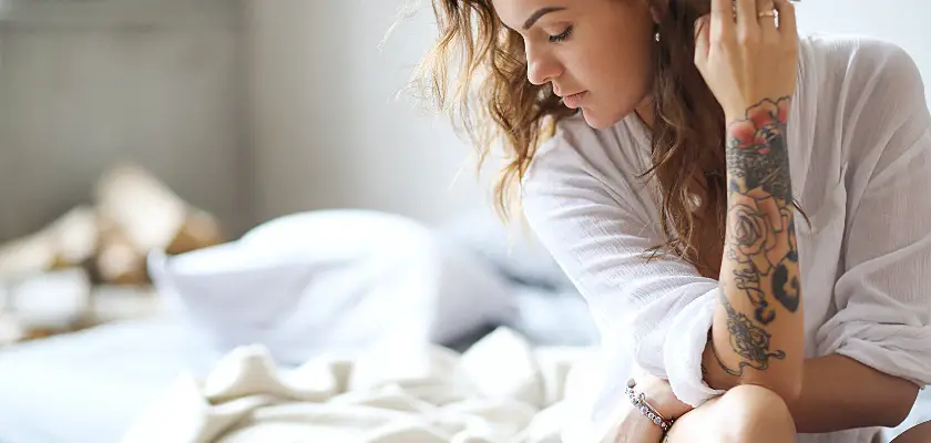 Giovane donna a letto al mattino – Quando fare un tatuaggio