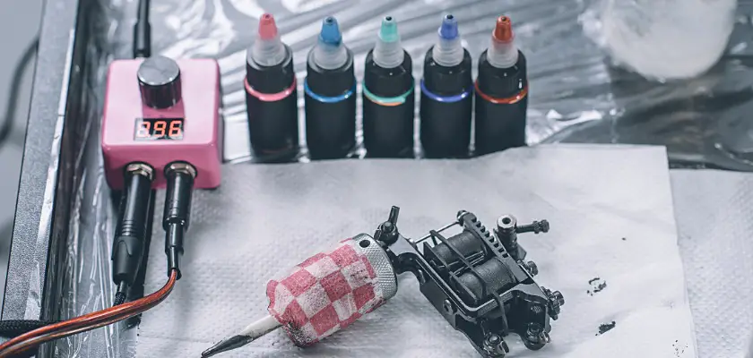 Vista di una macchina e diverse bottigliette con inchiostro colorato per tatuaggio