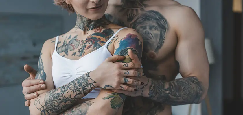 Vista ritagliata di una tenera coppia tatuata che si abbraccia in camera da letto